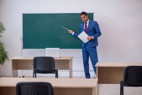 Yeşil panonun önünde takım elbiseli genç bir öğretmen. — Stok fotoğraf