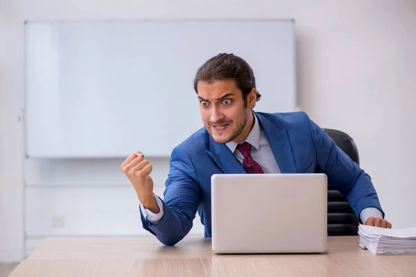 Jovem funcionário do sexo masculino sentado no escritório em frente ao quadro branco — Fotografia de Stock