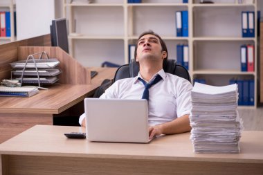 Ofisteki aşırı işten memnun olmayan genç bir erkek işçi.