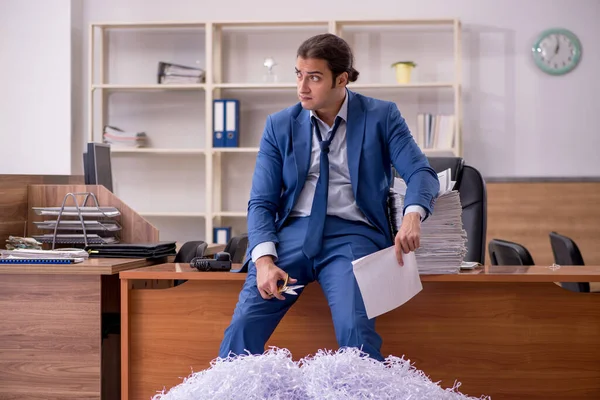 Junge männliche Angestellte und viele geschnittene Papiere im Büro — Stockfoto