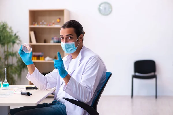 Jonge mannelijke chemicus werkzaam in het lab tijdens een pandemie — Stockfoto