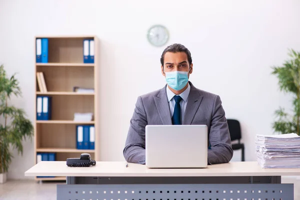 Młody mężczyzna pracownik nosi maskę podczas pandemii — Zdjęcie stockowe