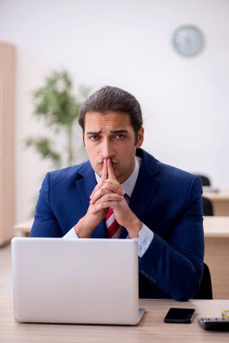 Genç erkek çalışan ofiste oturuyor.