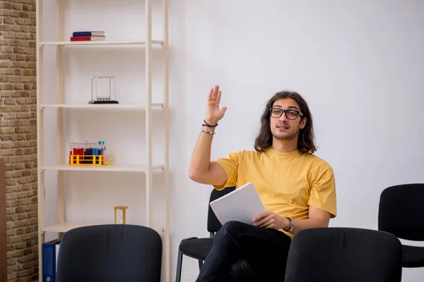 Jonge mannelijke student wachtend op leraar in de klas — Stockfoto