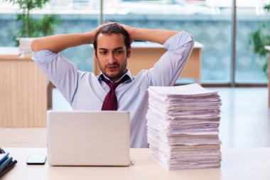 Ofisteki aşırı işten memnun olmayan genç bir erkek işçi.