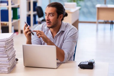 Ofisteki aşırı işten memnun olmayan genç bir erkek işçi.