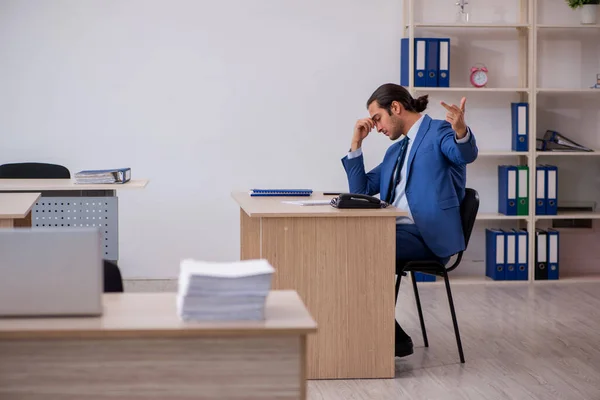 Joven empleado masculino y demasiado trabajo en la oficina —  Fotos de Stock