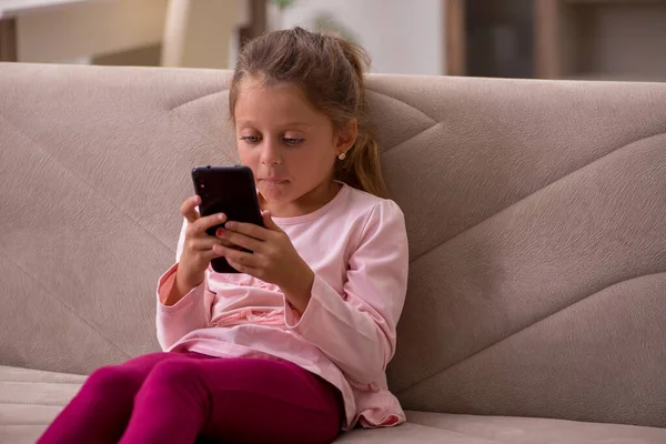 スマートフォンを持っている小さな女の子待っていますのために両親自宅 — ストック写真