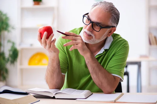 Старий студент їсть яблуко під час підготовки до іспиту — стокове фото