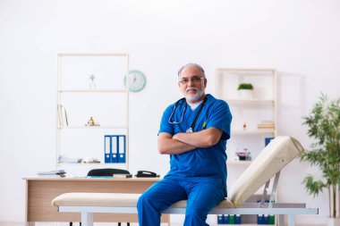 Klinikte çalışan yaşlı erkek doktor.