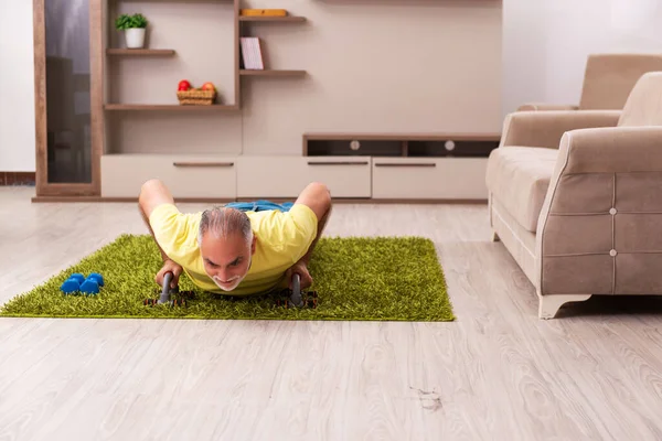 Uomo anziano che fa esercizi sportivi a casa — Foto Stock