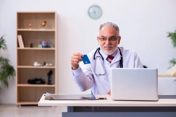 Old male doctor holding credit card — Stock Photo, Image
