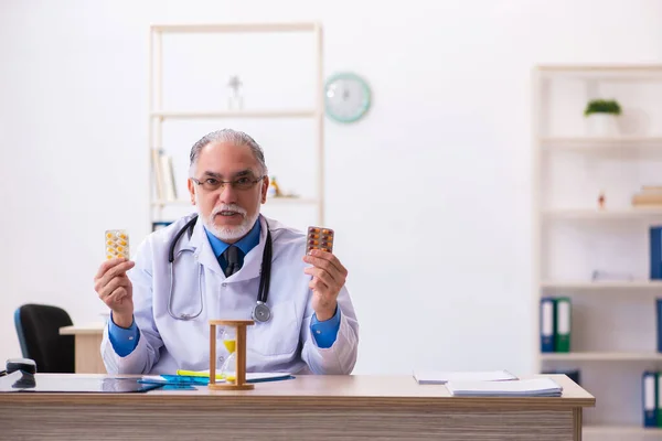 Παλαιός άνδρας γιατρός γράφει συνταγή στην κλινική — Φωτογραφία Αρχείου