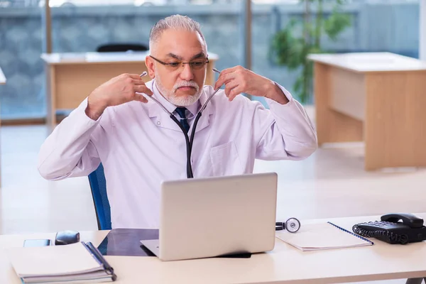 Oude mannelijke arts werkzaam in de kliniek — Stockfoto