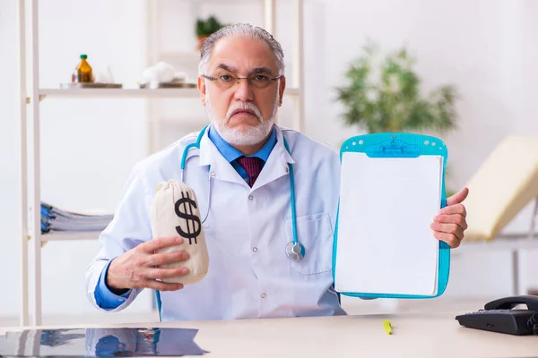 Yaşlı doktor hastanede para çantasını tutuyor. — Stok fotoğraf