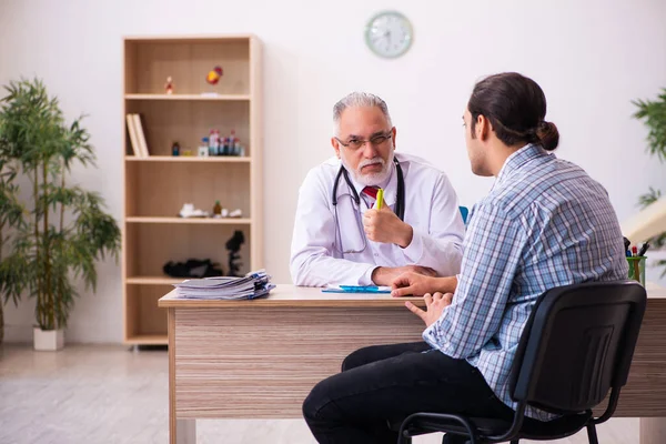 Young male patient visiting aged male doctor — Stock Photo, Image