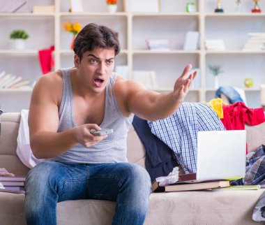 Genç adam dağınık bir odada çalışıyor.