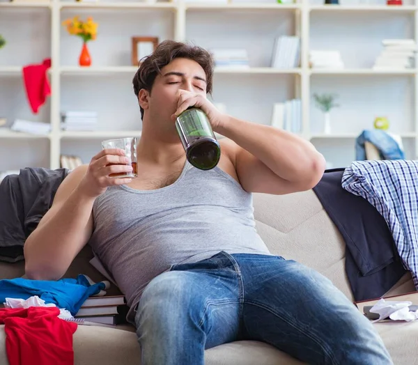 Giovane studente ubriaco bere alcol in una stanza disordinata — Foto Stock