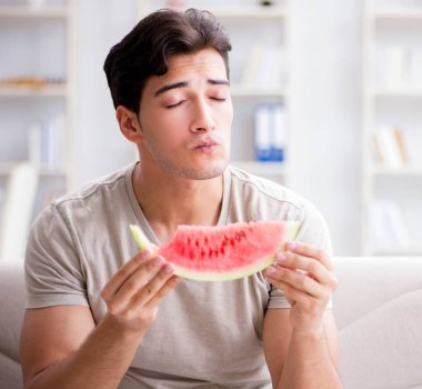 Evde karpuz yiyen bir adam.