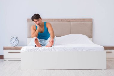 Genç adam yatakta uyanıyor.