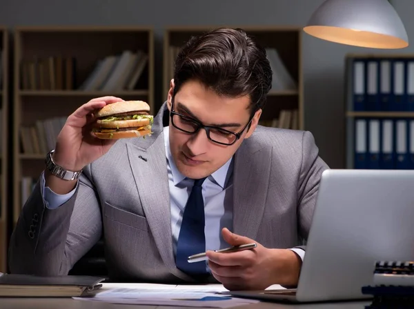 ビジネスマンは夜遅くハンバーガーを食べて — ストック写真