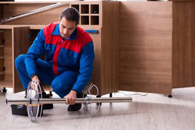 Genç yakışıklı erkek marangoz içeride çalışıyor.