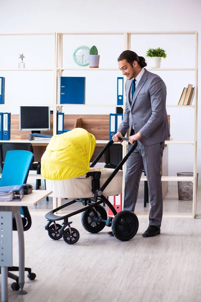 Joven empleado masculino que cuida del recién nacido en el lugar de trabajo — Foto de Stock