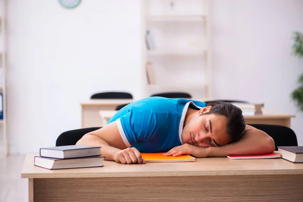 Uitgeputte mannelijke student bereidt zich voor op de examens in de klas — Stockfoto