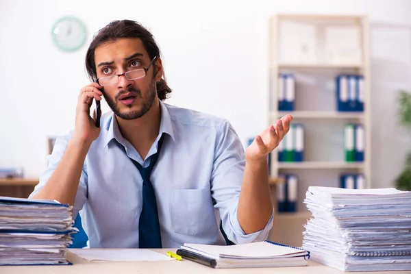 Jonge mannelijke werknemer ongelukkig met overmatig werk in het kantoor — Stockfoto