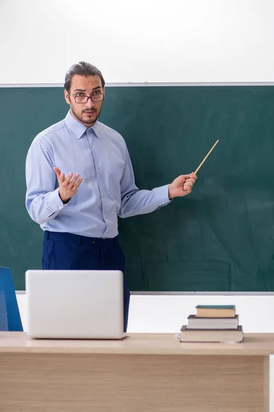 Joven profesor en el aula delante de la mesa verde —  Fotos de Stock