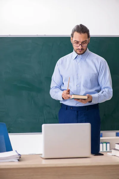 Jeune enseignant masculin dans la salle de classe devant le panneau vert — Photo