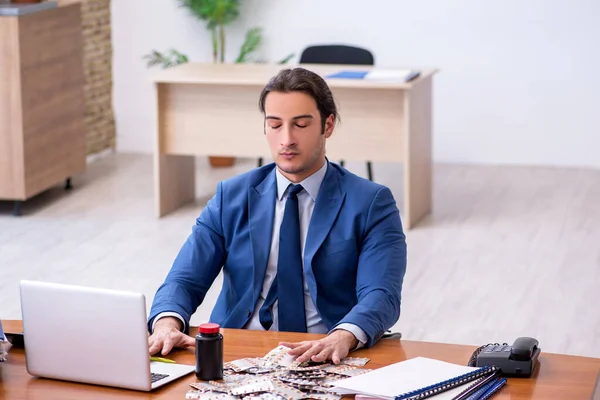 Jonge mannelijke zieke werknemer die op het werk lijdt — Stockfoto