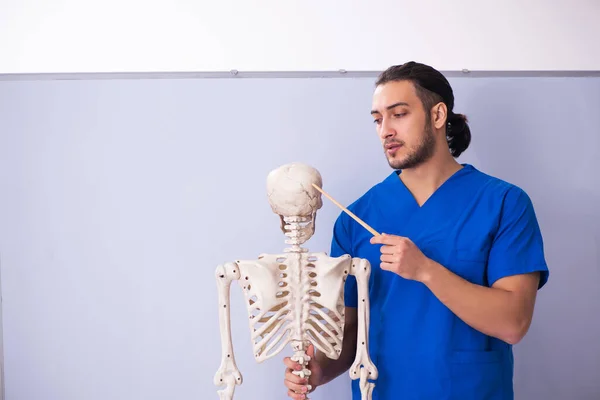 Giovane docente maschio con scheletro davanti alla lavagna — Foto Stock