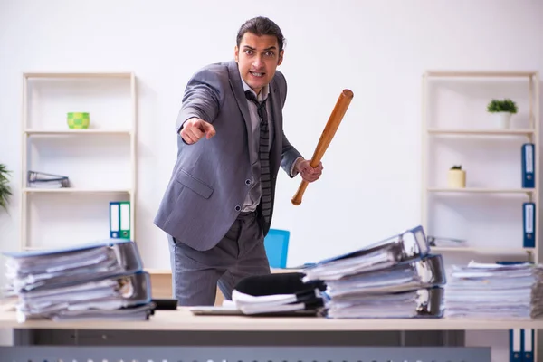 Young employee angry with excessive work holding baseball bat — Stock Photo, Image