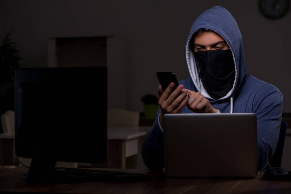 Male hacker hacking security firewall late in office