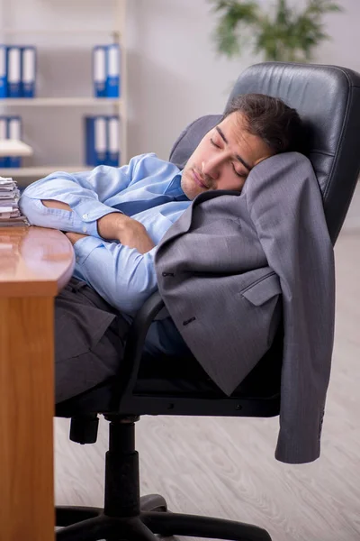 Ung mandlig medarbejder sover på kontoret - Stock-foto