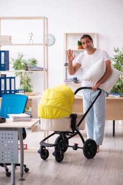 İş yerinde yeni doğan bebeğe bakan genç bir erkek işçi.