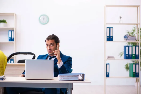 Jonge mannelijke werknemer zorgt voor kind op het werk — Stockfoto