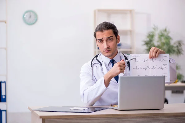 Young male doctor looking electrocardiogram in the clinic — Stock Photo, Image