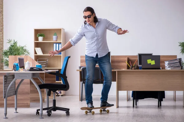 Jovem funcionário masculino com skate no escritório — Fotografia de Stock