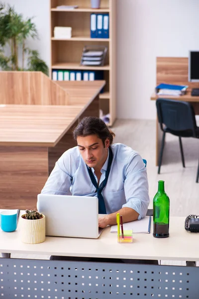 Junge männliche Angestellte trinkt Alkohol am Arbeitsplatz — Stockfoto