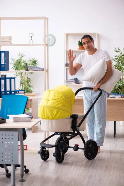 İş yerinde yeni doğan bebeğe bakan genç bir erkek işçi.