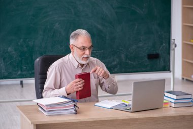 Sınıfta oturan yaşlı erkek öğretmen.