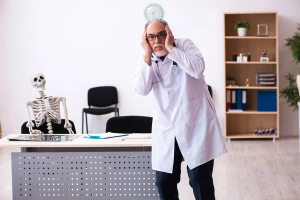 Vieux médecin masculin et patient squelette à la clinique — Photo