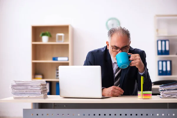 Gamle affärsman dricker kaffe på arbetsplatsen — Stockfoto