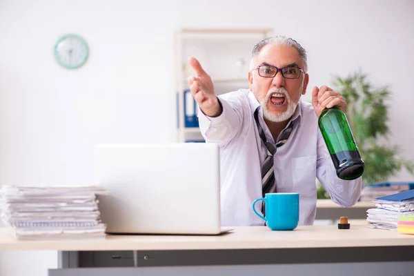 Stary pracownik pije alkohol w biurze. — Zdjęcie stockowe