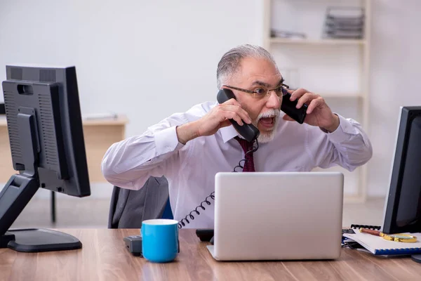 Vecchio capo maschio seduto sul desktop in ufficio — Foto Stock