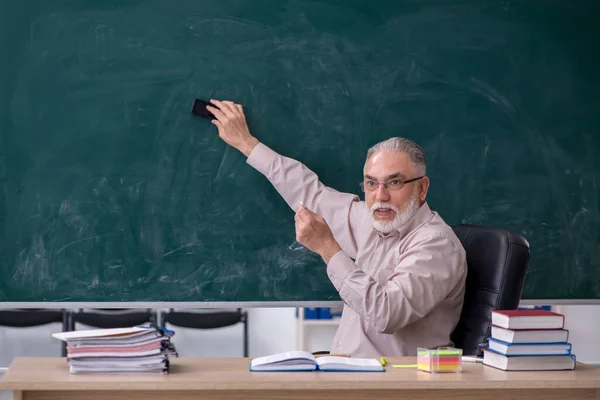 Oude mannelijke leraar zit in de klas — Stockfoto