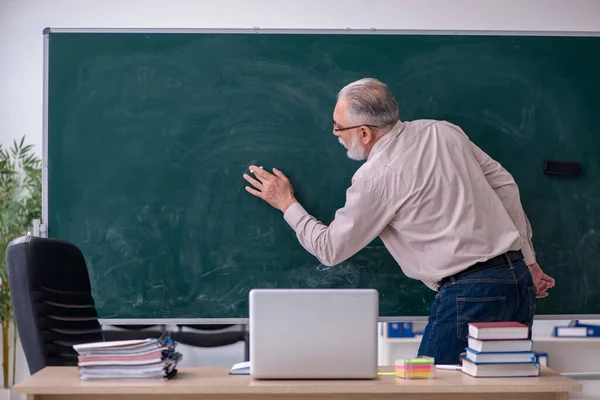 Egy öreg férfi tanár ül az osztályteremben. — Stock Fotó