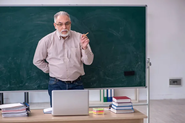 Oude mannelijke leraar zit in de klas — Stockfoto